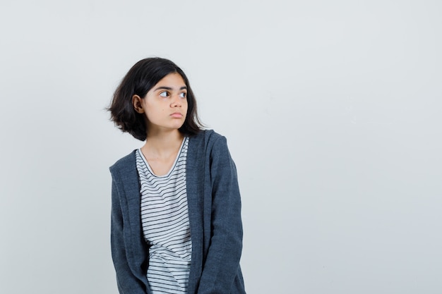 Meisje opzij kijken in t-shirt, jasje en peinzend kijken.