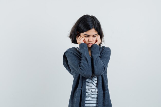 Meisje oren met vingers in t-shirt, jasje inpluggen en depressief kijken.