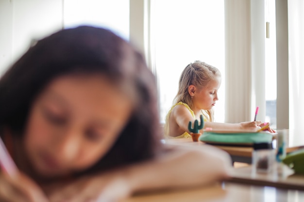 Meisje pennen zitten op school bureaus