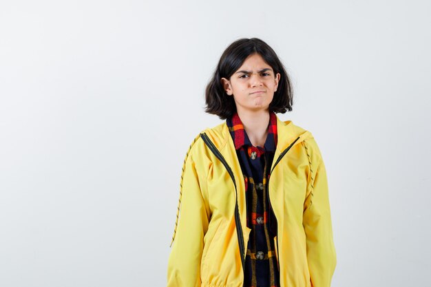 Meisje poseren terwijl ze in een geruit overhemd, jasje staat en weemoedig kijkt