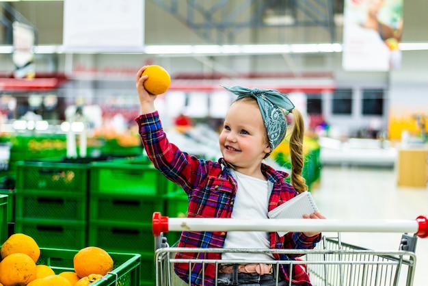 Meisje sinaasappelen uitkiezen in de supermarkt
