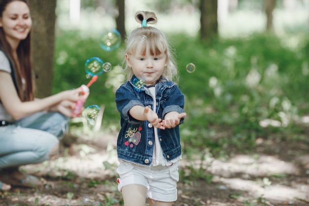 Meisje speelt met zeepbellen met haar moeder achter