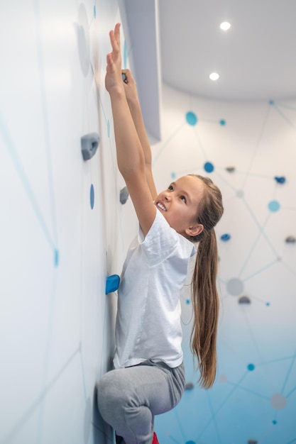 Gratis foto meisje strekt hand uit naar richel op klimmuur