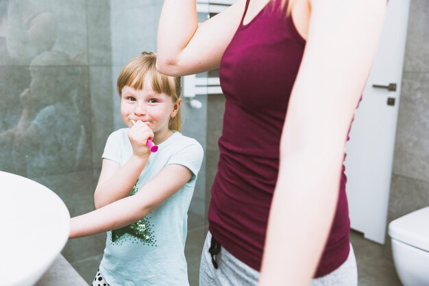 Gratis foto meisje tanden poetsen in de buurt van moeder