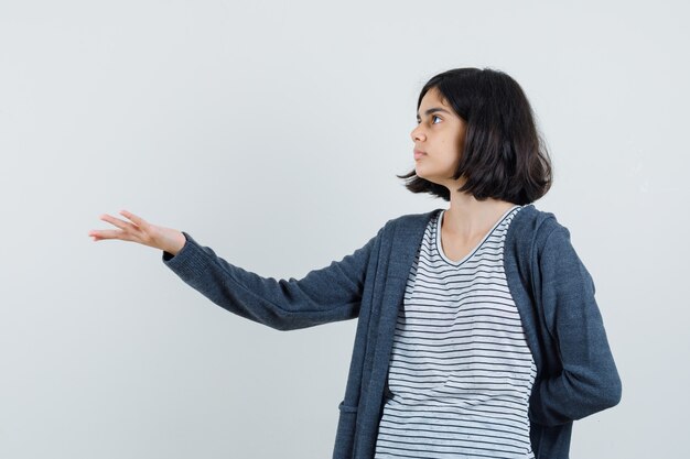 Meisje uitrekkende hand op vragende manier in t-shirt, jasje en op zoek verward