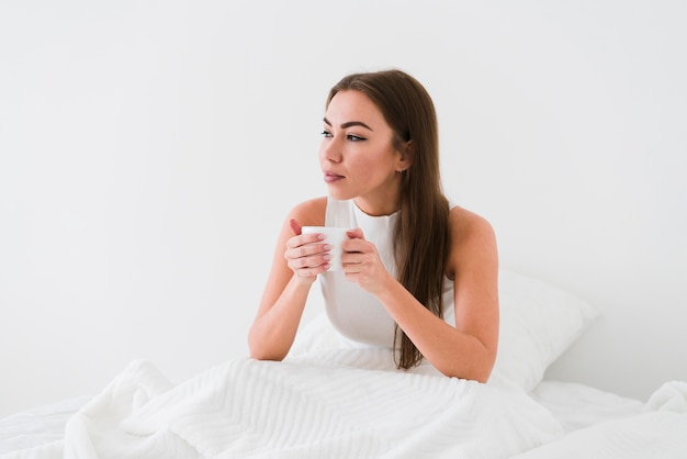 Meisje verblijft in bed en drinkt koffie