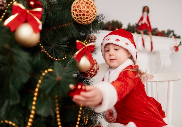 Meisje verkleed als kerstman versieren van de kerstboom