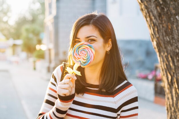 Meisje verstopt achter kleurrijke lollipop