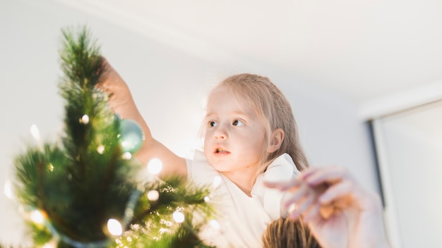 Gratis foto meisje wat betreft verlichte kerstboom