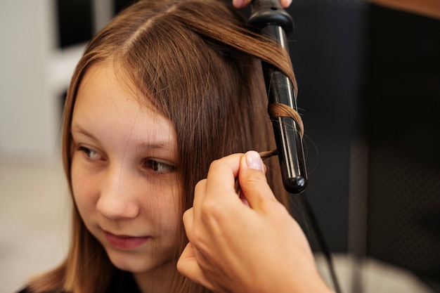 Meisje wordt gestyled in een hoge hoek van de salon