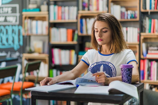 Meisje zit aan tafel met notitieboekjes studeren