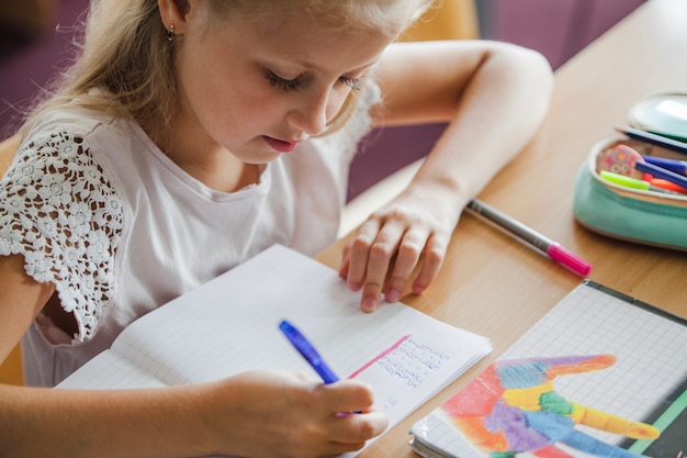 Gratis foto meisje zit bij bureau schrijven