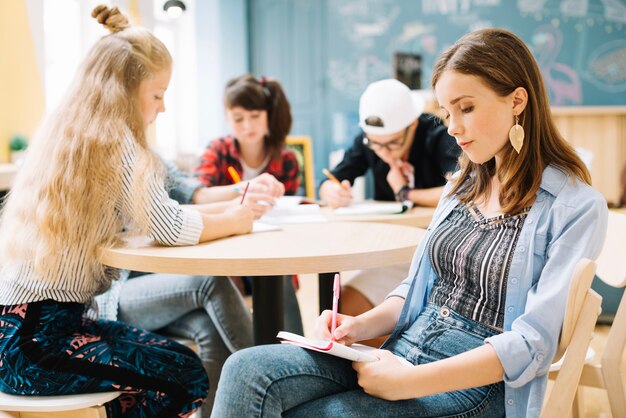 Meisje zitten en schrijven met klasgenoten