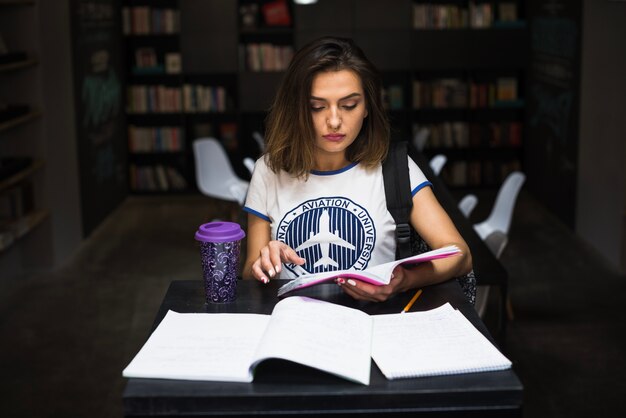 Meisje zittend aan tafel lezen notitieboekje lezen