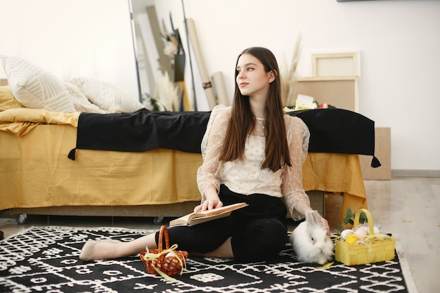 Meisje zittend op de vloer met een boek omringd door Pasen-thema's.