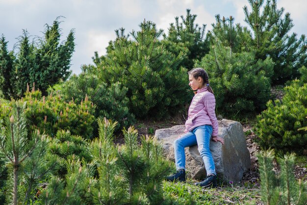 Meisje zittend op een rots buitenshuis