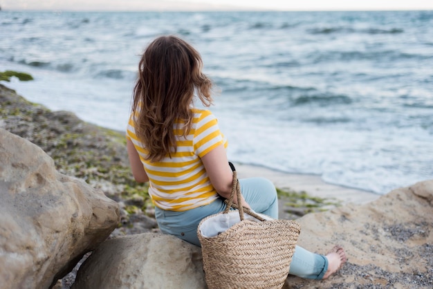 Gratis foto meisje zittend op rotsen met uitzicht op zee