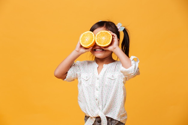Meisjekind die ogen behandelen met sinaasappel.