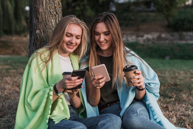 Meisjes die hun telefoons in park controleren