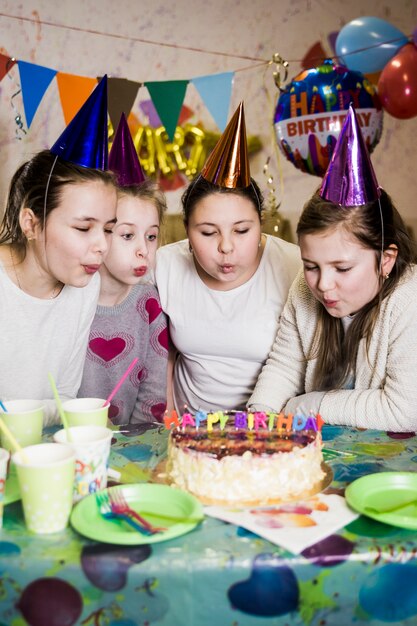 Meisjes die kaarsen op cake blazen