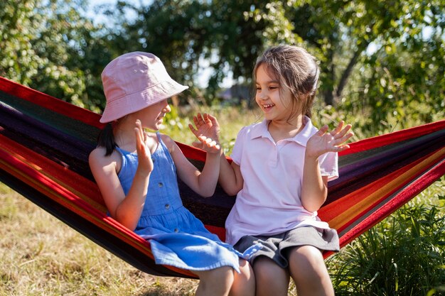 Meisjes die samen buiten spelen en in een hangmat zitten