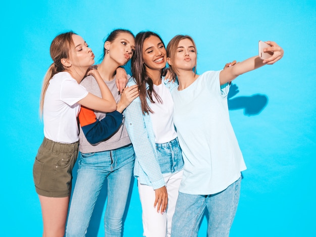 Meisjes die selfie zelfportretfoto's op smartphone nemen modellen die dichtbij blauwe muur in studio, wijfje stellen die positieve gezichtsemoties tonen