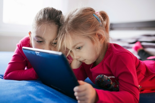 Meisjes die tablet op bed bekijken