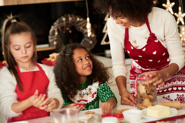 Meisjes helpen moeder koekjes maken voor Kerstmis