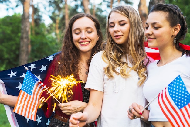 Gratis foto meisjes in de natuur met amerikaanse vlaggen en sparkler