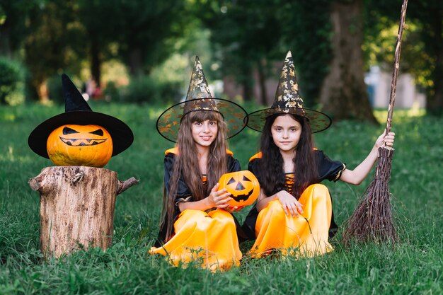 Meisjes in heksenkostuums die op gras in park zitten