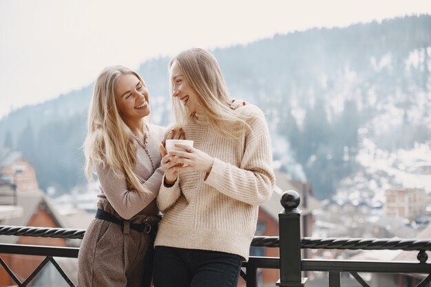 Meisjes in lichte kleren. Winterkoffie op balkon. Gelukkige vrouwen samen.