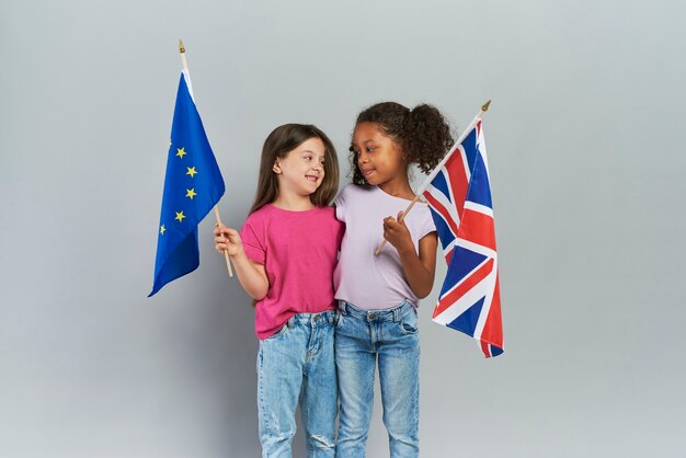 Meisjes omarmen en houden de vlaggen van de Britse en Europese Unie vast