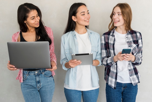 Gratis foto meisjes staan met gadgets in handen en kijken naar elkaar