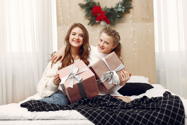 Meisjes zittend op het bed. Vrouwen met cadeau. De schoonheden bereiden zich voor op Kerstmis