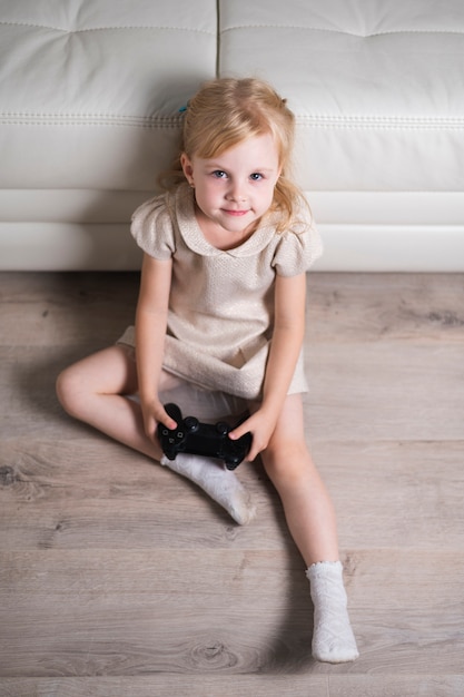 Gratis foto meisjeszitting op vloer en het spelen met joystick