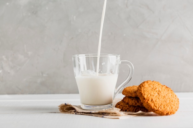 Melk gegoten in glas met koekjes