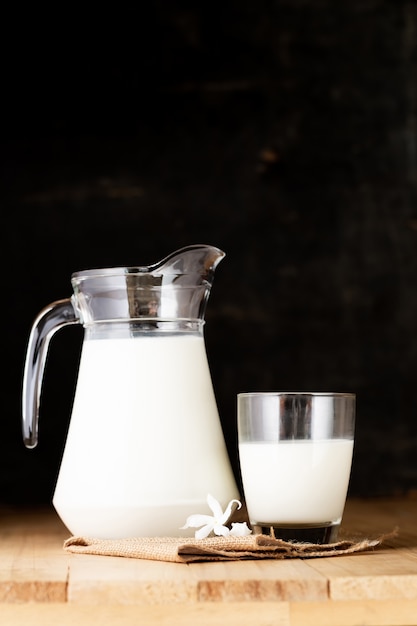 melk in glas en kruik op houten tafel