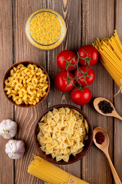 Meng pasta's op de houten tafel chifferi farfale linguini tomaat peper bovenaanzicht