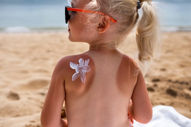 Mening van jong meisje bij het strand met lotion op zonnebrandhuid