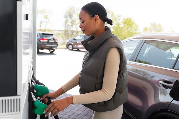 Mening van vrouw met auto bij het benzinestation