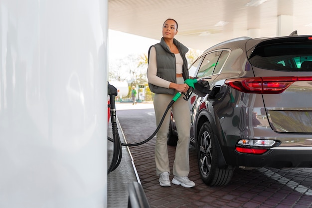 Gratis foto mening van vrouw met auto bij het benzinestation