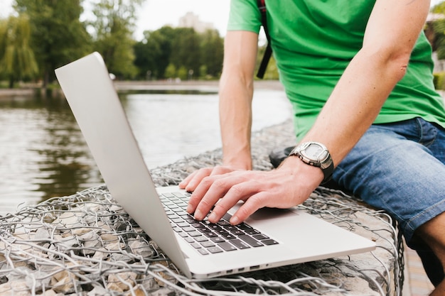 Gratis foto mens die aan laptop door het meer werkt