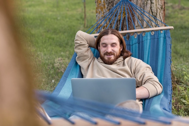 Mens die aan laptop werkt terwijl het zitten in hangmat