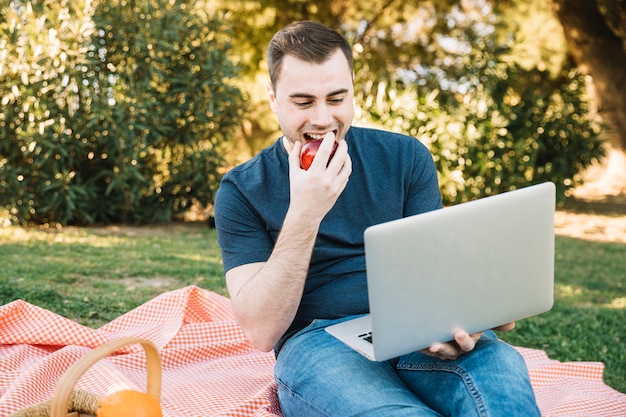 Gratis foto mens die appel eet en laptop met behulp van