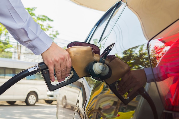 Mens die benzinebrandstof zet in zijn auto in een pompbenzinestation