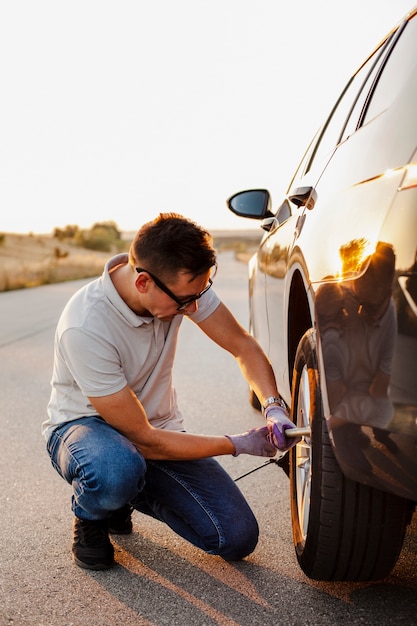 Mens die de bouten van het autowiel aanhaalt