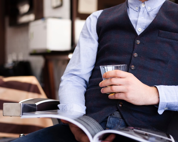 Mens die een glas whisky houdt bij het close-up van de kapperswinkel