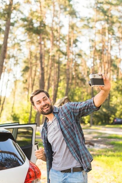 Mens die foto naast auto neemt