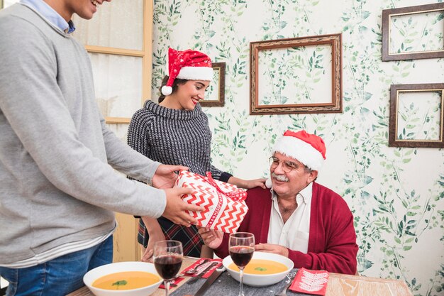 Mens die giftdoos geeft aan de oude mens in rode Kerstmanhoed