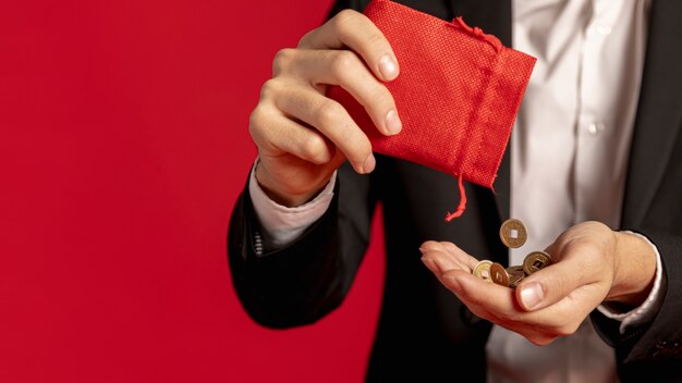 Mens die gouden muntstukken met rode zak houdt voor Chinees nieuw jaar